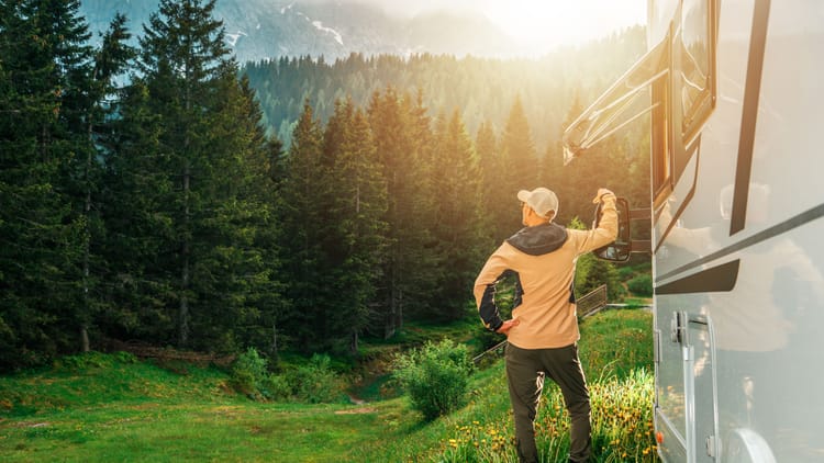 man enjoying the morning sun near an rv in a mountain forest while national park RV camping in the west